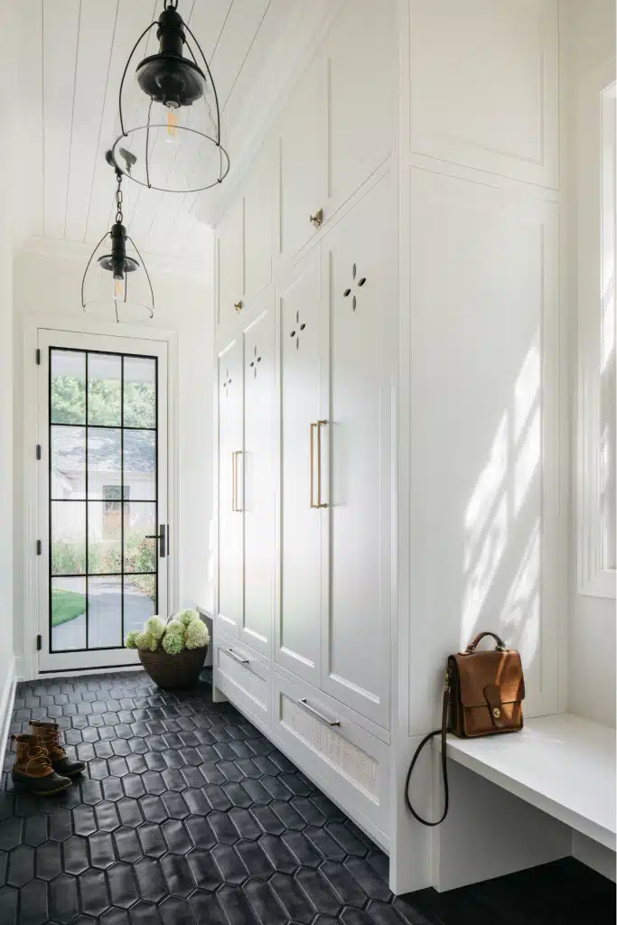 white and bright mudroom, black tiled mudroom, die-cut lockers, carriage house, winneka remodel, milly and o'malley design, modern industrial pendants